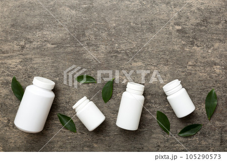 supplement pills with medicine bottle health care and medical top view. Vitamin tablets. Top view mockup bottle for pills and vitamins with green leaves, natural organic bio supplement, copy space 105290573