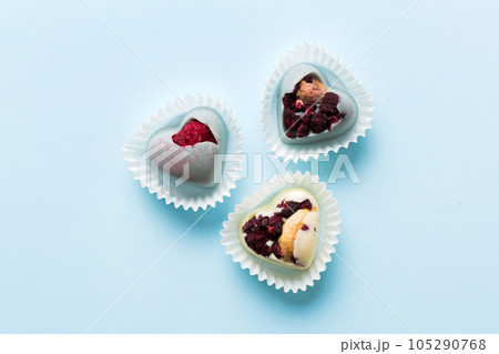 chocolate sweets in the form of a heart with fruits and nuts on a colored background. top view with space for text, holiday concept 105290768