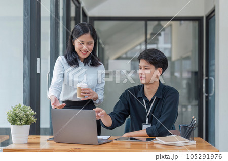 Two Asian colleagues are discussing the work. The businessman is laptop and tablet in office 105291976