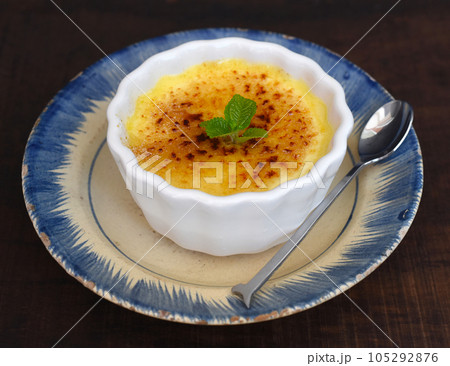 Creme brulee  in a ceramic bowl on wooden table and black background  105292876