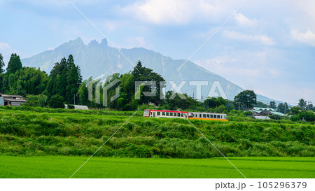 南阿蘇白川水源駅周辺からパノラマ撮影「全線開通・運航再開」(阿蘇山　山並みを背景に田園と列車風景) 105296379