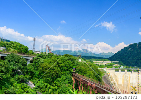 阿蘇山を背景に鉄橋を横断するトロッコ列車風景「全線開通・運航再開」(立野駅・立野ダム周辺から撮影) 105297173