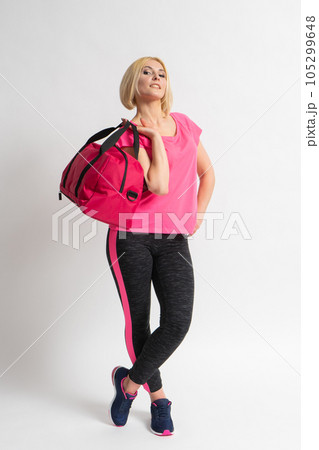 Woman in sportswear and sneakers holding a fitness training bag in her hands 105299648