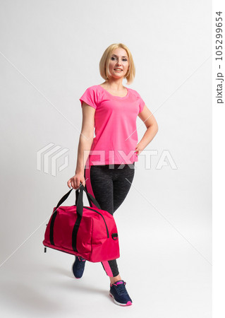 Woman in sportswear and sneakers holding a fitness training bag in her hands 105299654