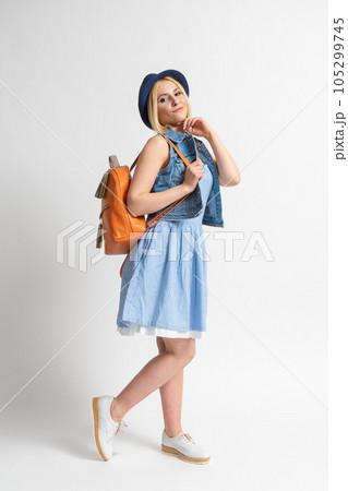 Woman in a summer dress with a hat and a backpack in the image of a tourist Woman in a summer dress with a hat and a backpack in the image of a tourist 105299745