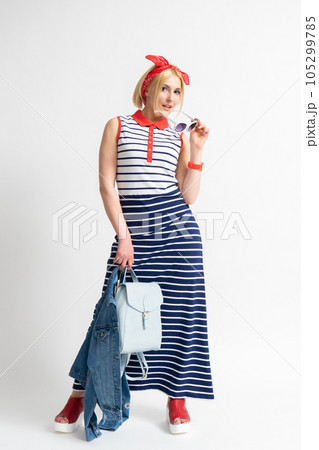 Woman in a striped dress with sunglasses and a denim jacket in her hand 105299785