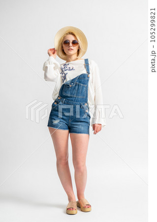 Woman in casual summer denim shorts, rustic blouse, straw hat and sunglasses 105299821