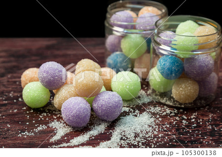 Portioned colored sugar scrubs balls folded into a glass jar and neatly laid out on a wooden table. Portioned colored sugar scrubs balls folded into a glass jar and neatly laid out on a wooden table. 105300138