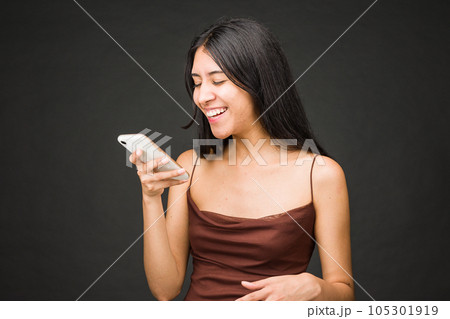 Positive friendly cheerful person holding cellphone. Young Latin female portrait. Beautiful brunette Positive friendly cheerful person holding cellphone. Young Latin female portrait. Beautiful brunette 105301919