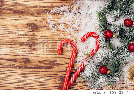Winter festive background with fir tree branches, snow and candy canes Winter festive background with fir tree branches, snow and candy canes 105303379