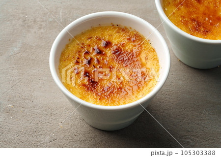 Creme brulee with caramel in two white bowls on gray background 105303388