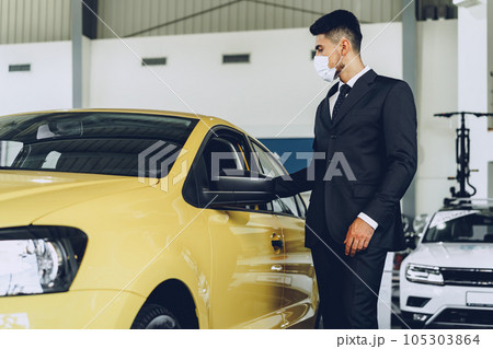 Man car dealer wearing protective medical mask on his working place Man car dealer wearing protective medical mask on his working place 105303864