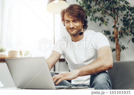 Young man businessman with headset working on laptop from home 105303935