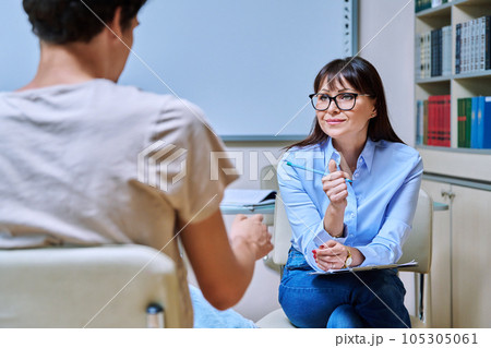 Middle-aged female psychologist working with young male in office 105305061