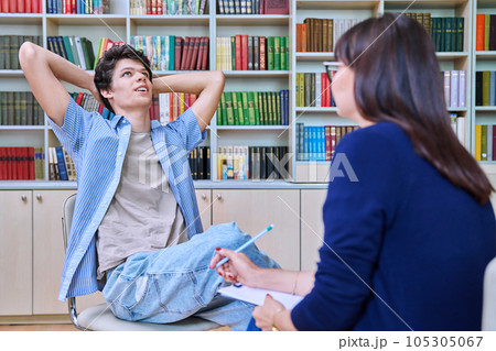 Female college counselor talking with young male student, meeting in library Female college counselor talking with young male student, meeting in library 105305067