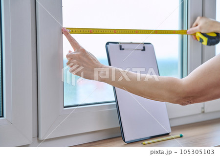 Woman measuring window with tape measure, tailoring service 105305103