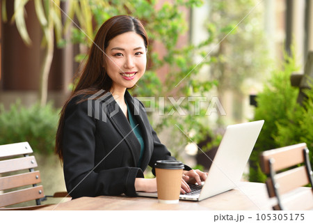 屋外でPCを操作する若いアジア人の女性 屋外でPCを操作する若いアジア人の女性 105305175