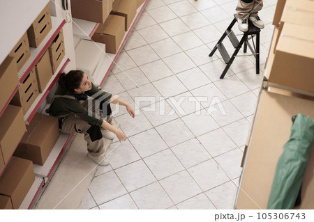Top view of warehouse employee standing on shelf in storage room, taking a break before start working at inventory. Small business worker preparing customers orders in storehouse 105306743