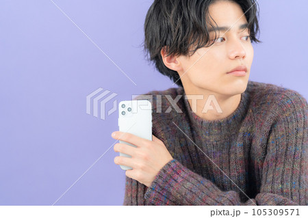 スマホを操作するパープルバックのニットを着た若い男性 105309571
