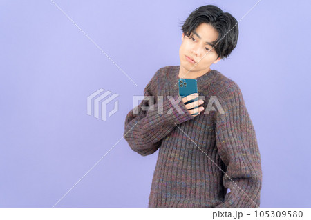 スマホを操作するパープルバックのニットを着た若い男性 105309580