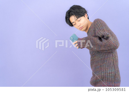 スマホを操作するパープルバックのニットを着た若い男性 105309581