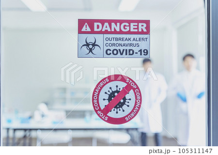 Biohazard disease alert corona outbreak sign on glass wall laboratory science center. Medical care clinic with hazard alert sign. Medical Healthcare concept. Biohazard disease alert corona outbreak sign on glass wall laboratory science center. Medical care clinic with hazard alert sign. Medical Healthcare concept. 105311147