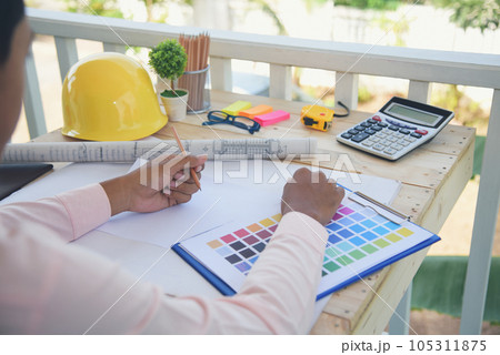 close up construction engineer man hands working at office desk architect workplace. Engineer Men hands drawing holding folder, use smartphone on office table drawing document blueprint hard hat close up construction engineer man hands working at office desk architect workplace. Engineer Men hands drawing holding folder, use smartphone on office table drawing document blueprint hard hat 105311875