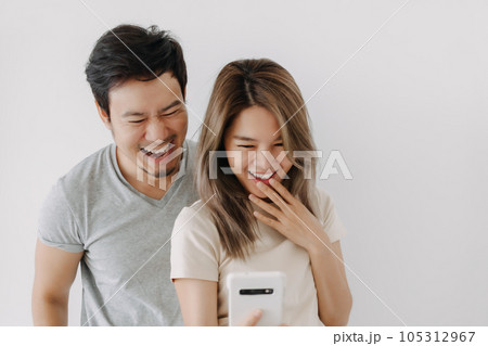 Funny couple lover laugh at the clip in the smartphone isolated on white. Funny couple lover laugh at the clip in the smartphone isolated on white. 105312967