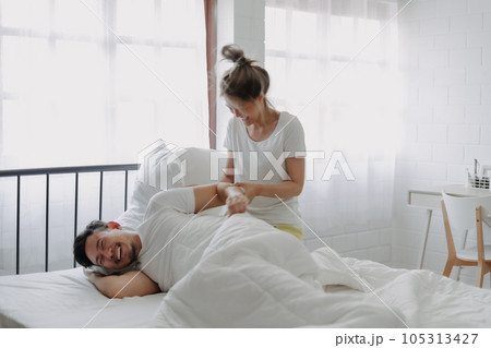 Funny couple morning wake up fight between wife and lazy husband. 105313427