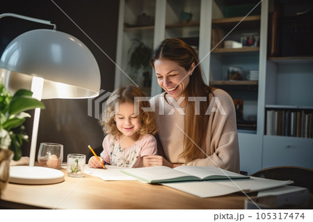 Happy child and adult are sitting at desk. Girl doing homework or online education 105317474