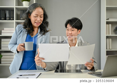 A happy Asian senior female boss is co-working on a new project with a young male worker A happy Asian senior female boss is co-working on a new project with a young male worker 105319884