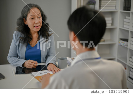 A male worker is having a serious conversation while handing his resignation letter to his boss 105319905