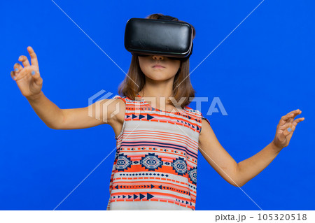 Child kid girl using headset helmet app to play simulation game, watching virtual reality 3D video Child kid girl using headset helmet app to play simulation game, watching virtual reality 3D video 105320518