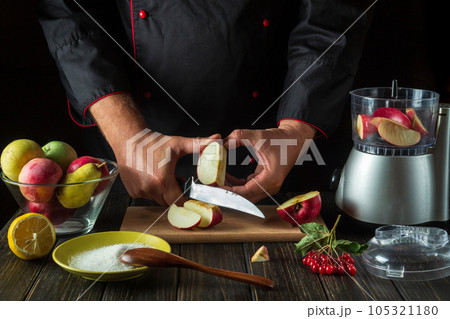 The chef cuts an apple to prepare a sweet fruit drink in a blender or mixer. Menu or recipe idea for a healthy vegetarian breakfast or dinner 105321180