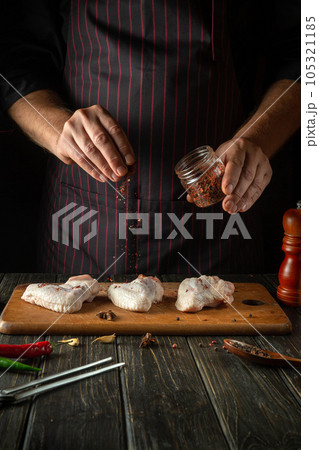 The chef adds aromatic spices to raw chicken wings. Cooking chicken nugget in the restaurant kitchen The chef adds aromatic spices to raw chicken wings. Cooking chicken nugget in the restaurant kitchen 105321185