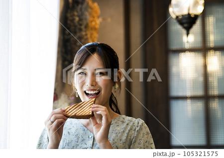 カフェでパンを食べる若い女性　カメラ目線 105321575