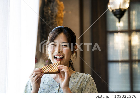 カフェでパンを食べる若い女性　カメラ目線 105321576