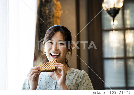 カフェでパンを食べる若い女性　カメラ目線 105321577