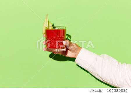 Lady's hand holding glass of blood Mary on light violet background. Contemporary pop art banner. Lady's hand holding glass of blood Mary on light violet background. Contemporary pop art banner. 105329835
