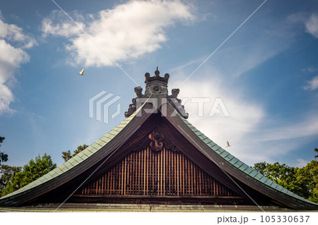 梅宮大社の夏、アオサギの飛ぶ夏空と拝殿の屋根 105330637