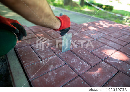 A worker aligns the gaps between the individual paving blocks. 105330738