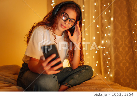 Woman in headphones before bedtime listening online to relaxing music. Remote work, internet concept 105331254