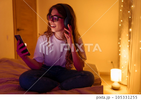 Woman in headphones before bedtime listening online to relaxing music. Remote work, internet concept Woman in headphones before bedtime listening online to relaxing music. Remote work, internet concept 105331255