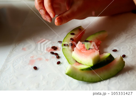 A woman enjoys a delicious watermelon, holding a slice in her hand at home. The close-up captures the vibrant colors and juicy texture of the fruit. After food. Out of focus 105331427