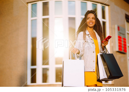 Young woman with shopping bags walking on street. Sale, shopping and happy people concept. 105331976