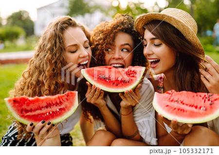 Cheerful happy friends camping on the grass, eating watermelon, laughing. Cheerful happy friends camping on the grass, eating watermelon, laughing. 105332171