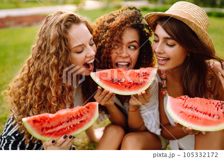 Cheerful happy friends camping on the grass, eating watermelon, laughing. Cheerful happy friends camping on the grass, eating watermelon, laughing. 105332172