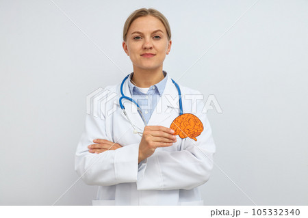 A young female doctor holds a paper human brain in her hand 105332340
