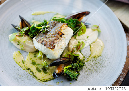 Cod fillet with cauliflower cream, asparagus, clam-wine sauce and mussles. Delicious seafood fish closeup served on a table for lunch in modern cuisine gourmet restaurant 105332798