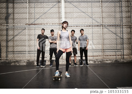 hipster young asian woman posing outdoors with skateboard and four male friends 105333155